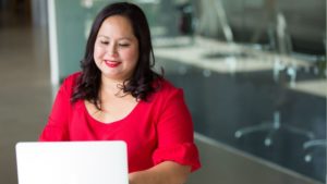 woman sat at desk in front of her laptop (working on cv to help her get promoted to senior management)