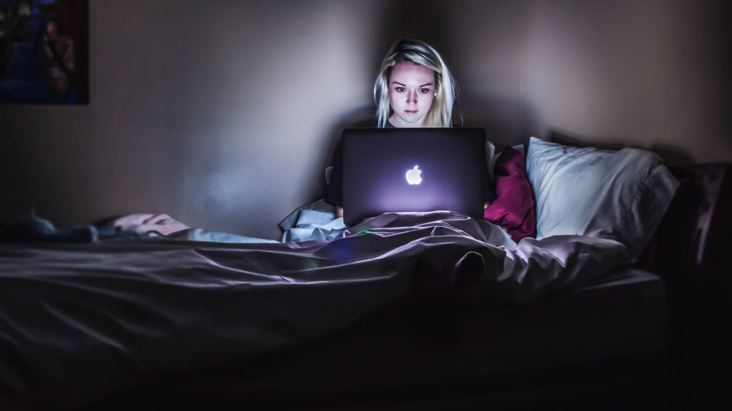 woman, sat in bed, working on laptop late at night