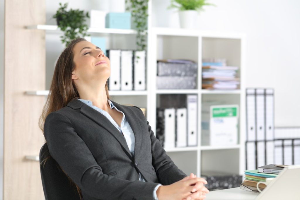 mindfulness - introverted business woman sat back in chair relaxing