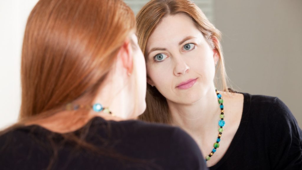 woman looking in mirror (self awareness)