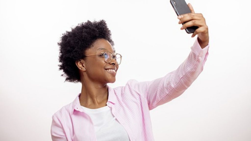 Woman with Smartphone Taking Selfie to Illustrate 4 Ways Introverted Leaders Can Use LinkedIn Stories to Raise their Visibility and Profile