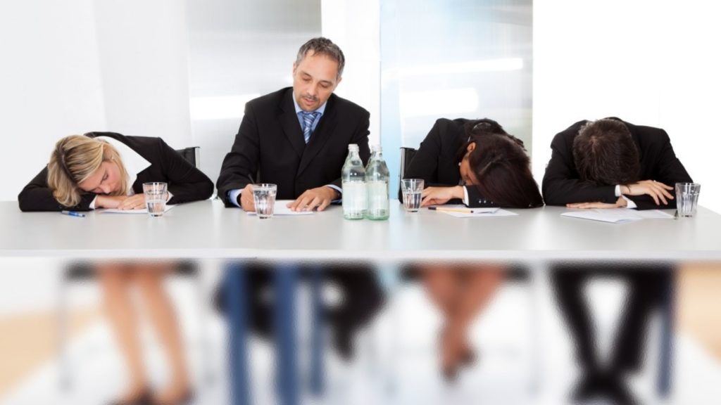 Group of people having a meeting and it is boring as people slump over onto the table